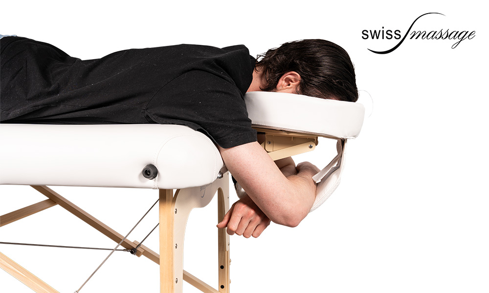 Personne couchée sur une table de massage avec la tête dans un kit têtière